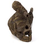 A West African voodoo type skull, partially strung with open mouth and shaped head, 32cm high.