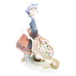 A 20thC Lladro figure of a girl pushing a wheelbarrow, polychrome decorated predominately in pink,