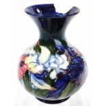 An early 20thC Moorcroft vase, of bulbous form, tube lined with flowers on blue ground, impressed