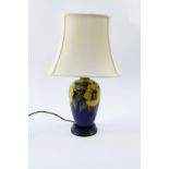 A Moorcroft Pottery table lamp decorated in the Golden Pansy pattern, against a blue ground with