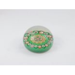 A Monart glass millefiori paperweight, with a central spoked wheel design, within an outer band,