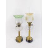 A duplex brass oil lamp, raised on a black pottery socle, with faceted clear glass reservoir and