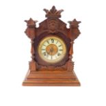 An American oak cased mantel clock, the circular brass dial with enamel chapter ring, bearing