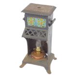 A Victorian cast iron Cathedral heater, inset with two floral tiles, containing a copper oil lamp,