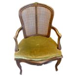 A late 19thC French beech open armchair, with a caned back, scroll carved arms, a green velvet squat