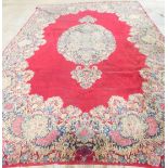 A large Kirman carpet, with a central medallion on a red ground, with floral borders and