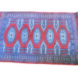 An Afghan rug, with a design of five medallions on a deep red ground with multiple borders, 96cm x