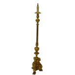 A gilt standard lamp in Continental style, with a fluted column and tri form base with paw feet,