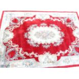 A large Chinese wool cut carpet, decorated with flowers leaves and scrolls, on a red ground, 365cm x