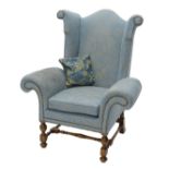 An unusual walnut wingback armchair, upholstered in pale blue and gold patterned fabric with studded