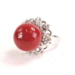 A Chinese dress ring, with a central deep red polished coral sphere in a floral and fruit design, on