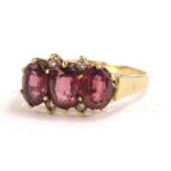 A 9ct gold dress ring, set with three garnets, and four tiny white stones, in claw setting, 3.4g all