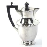A George V silver hot water jug, with shaped borders and ebonised knop handle, Sheffield 1910,