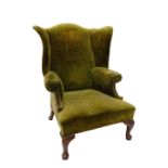 A George III style mahogany wingback armchair, upholstered in green textured floral velvet on