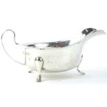 A George VI silver sauce boat, with a shaped border, loop handle and three feet, Sheffield 1939,