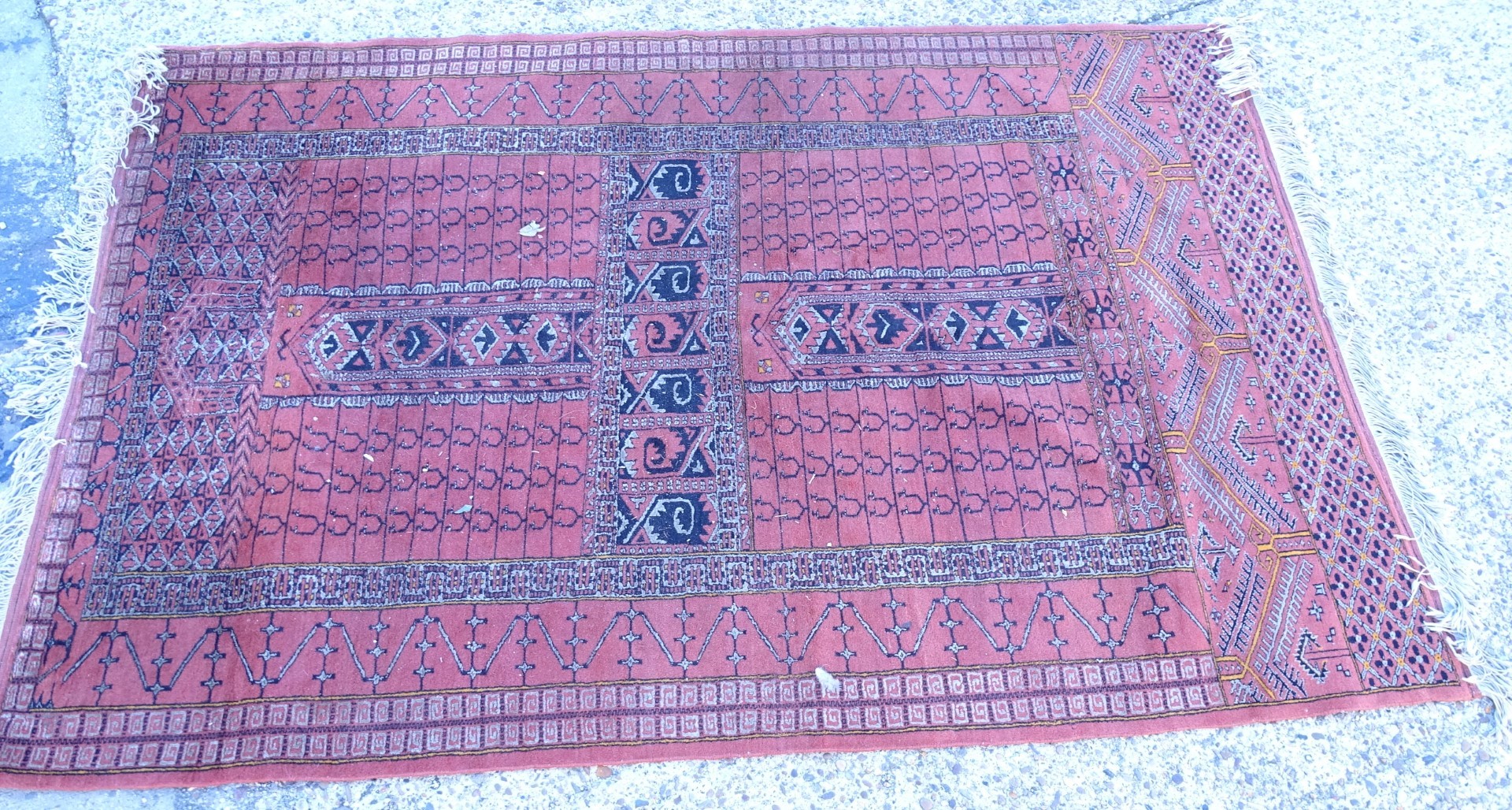 An Afghan style rug, with a central cross design on a deep pink ground with multiple borders,