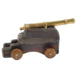 A 19thC small miniature cannon, with brass barrel, the base mahogany with horn button shaped