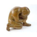 A carved wooden sculpture, modelled in the form of a crouching nude male, 29cm H, 37cm W.