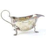 A George V silver sauce boat, with a shaped border, loop handle and three feet, Birmingham 1930,