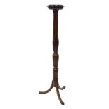 A mahogany torchere, the circular top with a lappet carved border on a part reeded and fluted column