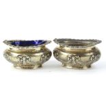 A pair of late Victorian oval silver salts, each with embossed decoration of ribbon swags etc, in