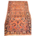 A Persian rug, with a design of flowers, on a rust coloured ground with multiple borders, 206cm x