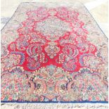 A large Kirman carpet, with a central medallion, on a red ground, with floral borders and spandrels,