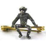 A silver white stone set seated monkey, on rolled gold bar brooch, lacking eye.
