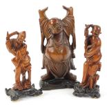 An oriental carved wooden model of pudai, on a pierced base and two similar figures, the largest