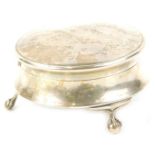 A small early 20thC silver trinket box, of circular form with ball and claw feet, marks