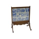 An unusual early 20thC mahogany firescreen, inset with blue and white tiles, decorated with scenes