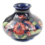 A Moorcroft floral decorated Fuscia pattern squat vase, with a deep blue coloured glaze, paper label