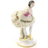 A German porcelain crinoline ballet dancer, leaning forward, with floral encrusting to her elaborate