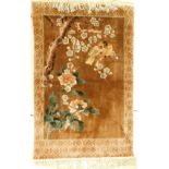 A Chinese silk type hanging, decorated with two birds in a flowering prunus tree, on a brown