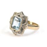 A 9ct gold blue topaz and diamond chip ring, having central emerald cut stone surrounded by stylised