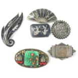 Various Oriental and Eastern white metal brooches, to include a black enamel engraved brooch, a