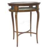 An Edwardian mahogany and marquetry oval display table, the hinged glazed top enclosing a lined