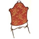 An Edwardian mahogany cartouche shaped firescreen, with a floral fabric banner, on shaped