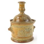 A 19thC stoneware jar and cover, the lid modelled as a candlestick, the base with two handles,