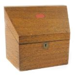 An early 20thC oak stationery box, the sloping hinged lid enclosing a fitted interior, 25cm W.