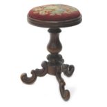 A Victorian walnut piano stool, the revolving circular seat with a floral padded woolwork, on turned