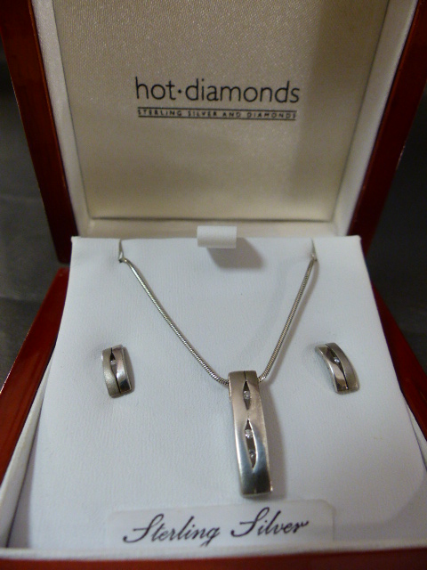 Sterling silver and boxed in their signature wooden case is a Hot Diamonds pendant and earrings set.
