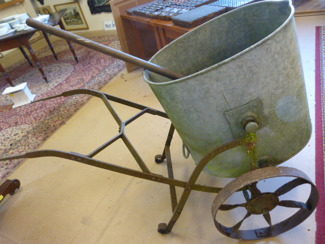 Large oval shaped galvanised water tank on antique cast iron frame with wheels