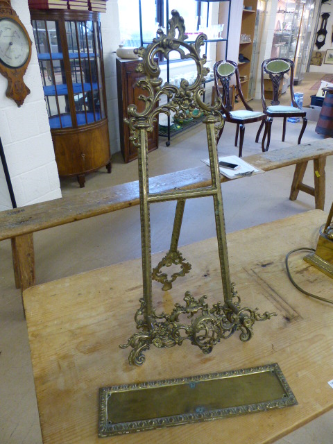 Unusual brass bookstand decorated with scrolls and flowers along with two similar door plates