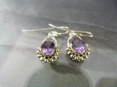 Pair of Amethyst earrings set in silver with balled decoration around the stone Total approx