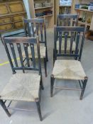 Set of four Arts and Crafts oak rush seated chairs with pierced slatted back.