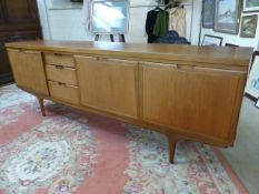 Large Mid Century Teak side board with pull down door, cupboards and drawers on stick legs