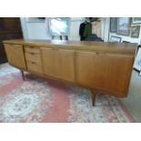 Large Mid Century Teak side board with pull down door, cupboards and drawers on stick legs