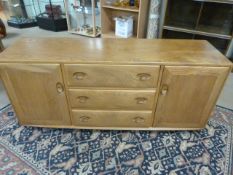 Ercol Blonde elm sideboard with three central drawers and two cupboards flanking.