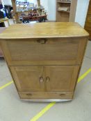 An Ercol light elm drinks cabinet with drop front and cupboard with single drawer